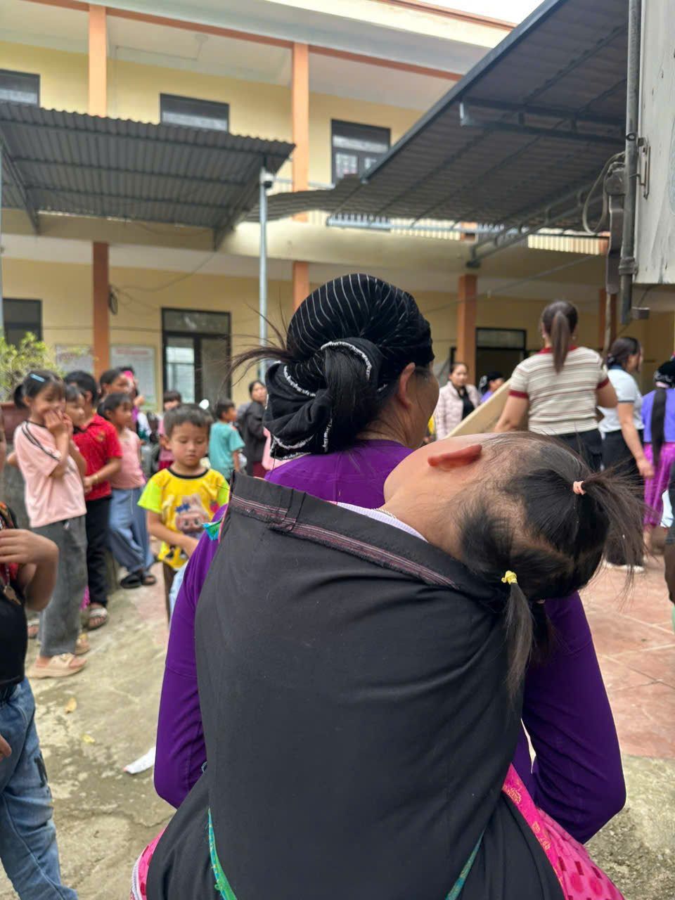 Người mẹ địu con nhỏ đến nhận quà
