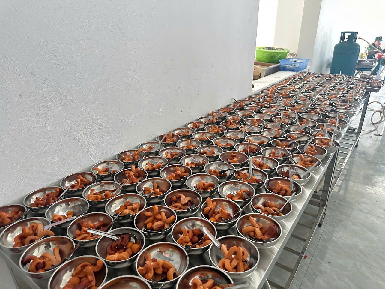 Hàng dài những bát cơm xếp trên bàn inox trong bếp